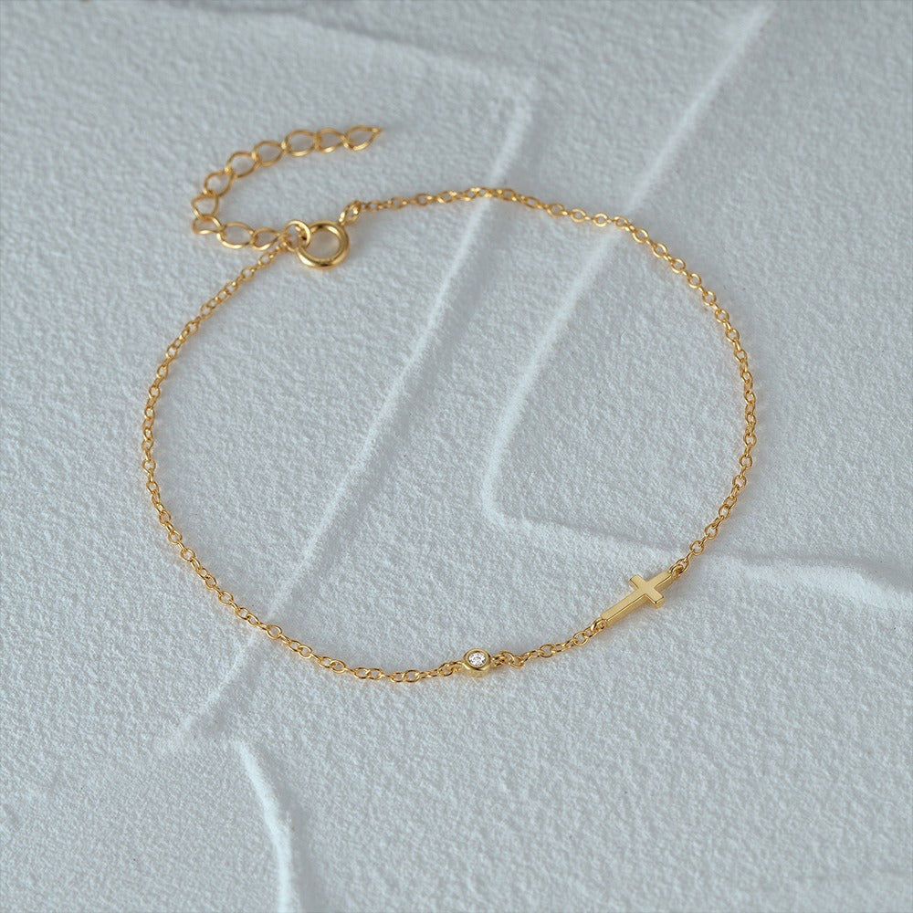 Dainty gold cross charm bracelet with CZ accent, styled as women's string bracelet
