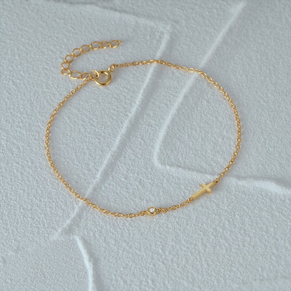 Dainty gold cross charm bracelet with CZ accent, styled as women's string bracelet