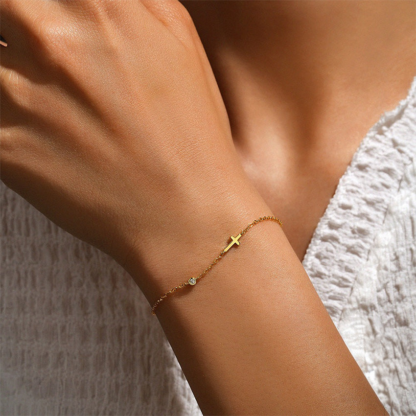 Elegant cross bracelet gold design with delicate chain and cubic zirconia, perfect for layering