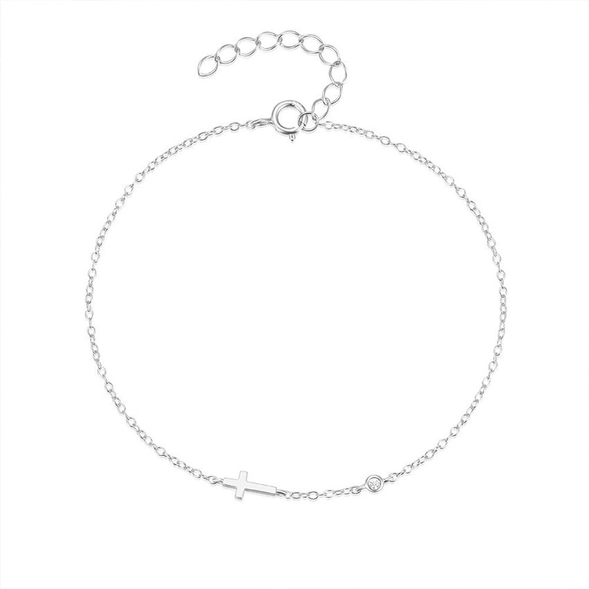 Close-up of gold cross charm bracelet with CZ detail on slim 925 silver chain for women