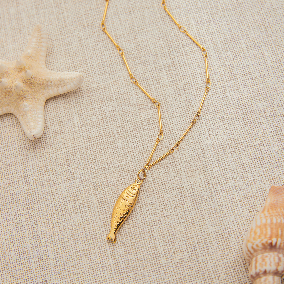 Detail view of fish pendant necklace sizing. Stainless steel necklace in ocean beach style, part of a vacation-ready matching jewelry set.