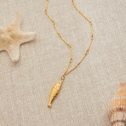 Detail view of fish pendant necklace sizing. Stainless steel necklace in ocean beach style, part of a vacation-ready matching jewelry set.