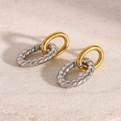 Close-up of two tone oval twist earrings on marble surface. Chunky stainless steel earrings in gold and silver for women, perfect for daily wear or wholesale jewelry collections.