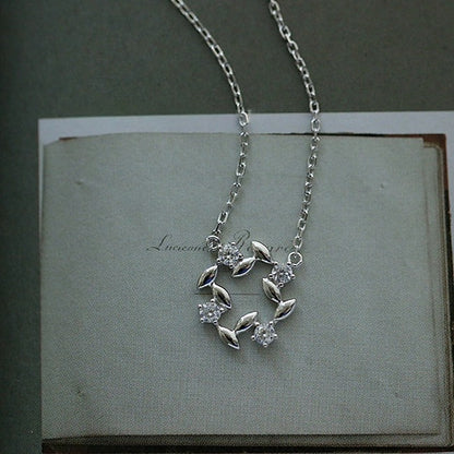 Close view of 14K gold plated leaf wreath zircon pendant necklace on book page