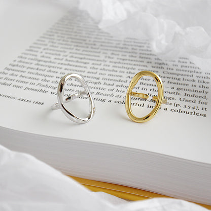 Gold and silver oval open rings placed on a book page, highlighting a set of 5 adjustable minimalist jewelry rings made for wholesale and everyday fashion collections.
