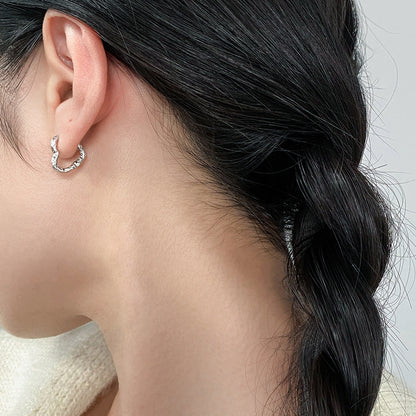 Model wearing wholesale 925 sterling silver textured heart shaped hoop earrings minimalist style