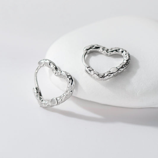 Wholesale silver 925 jewelry textured heart hoop earrings displayed on white stone background