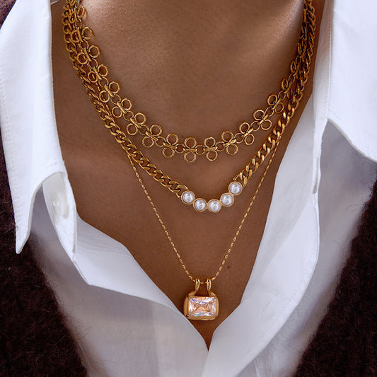 Model wearing gold statement layered necklace with loop link choker pearl chain and square zircon pendant
