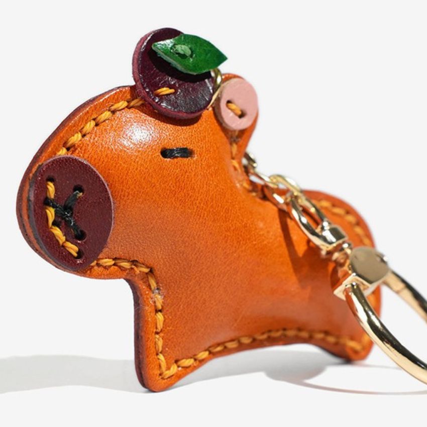 Close-up of leather capybara bag charm with gold keyring, ideal for handmade gift or senior graduation present