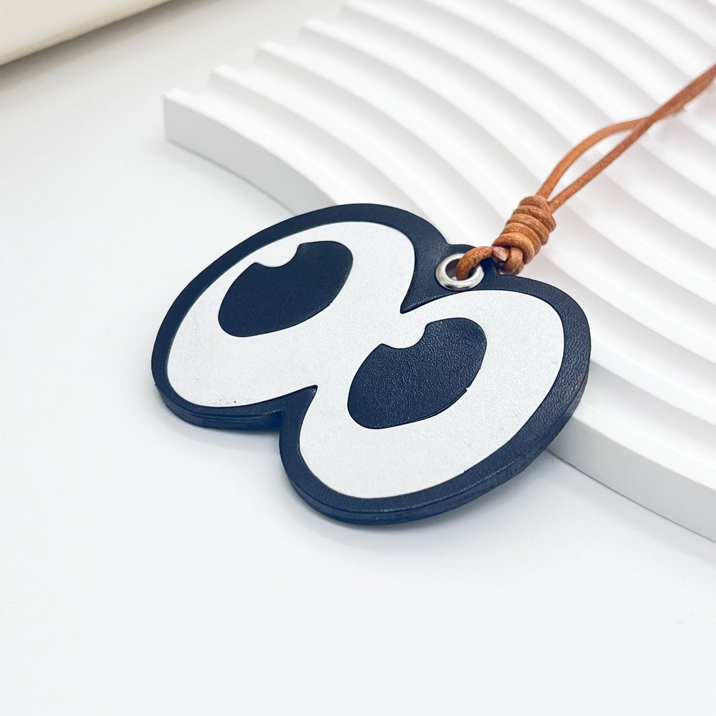 Side angle of cartoon eyes leather charm showing texture, thickness, and stitched detail