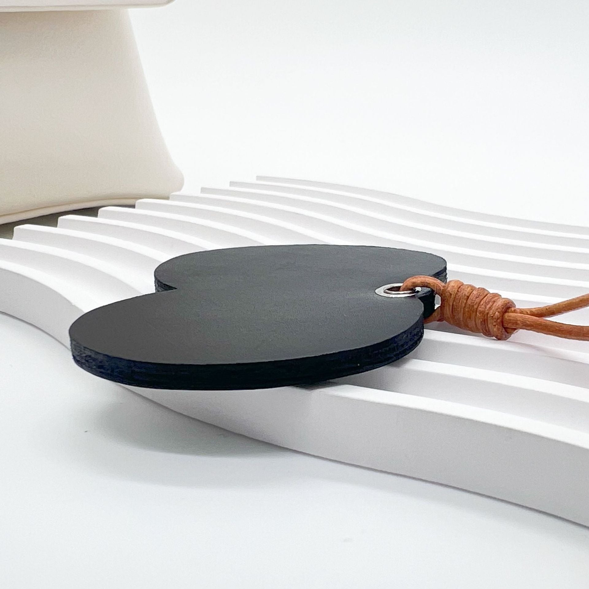 Back view of black genuine leather cartoon eyes bag charm with tan cord and metal ring