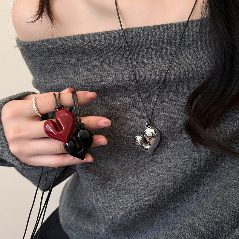 Model showing all three chunky heart pendant necklaces—red, black, and silver.