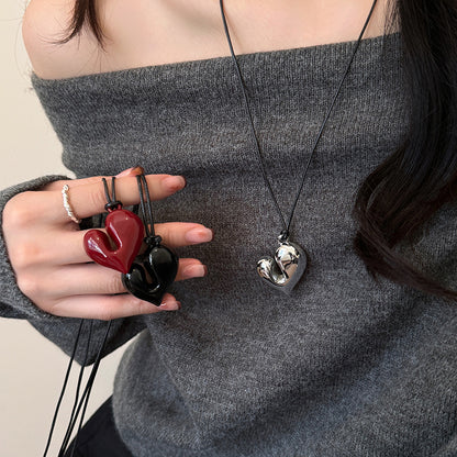 Model showing all three chunky heart pendant necklaces—red, black, and silver.