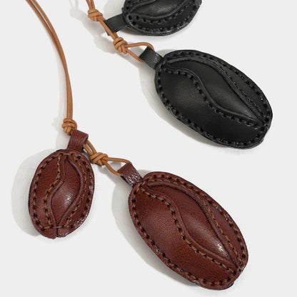 Black and brown leather coffee bean charms with keyring cords shown flat