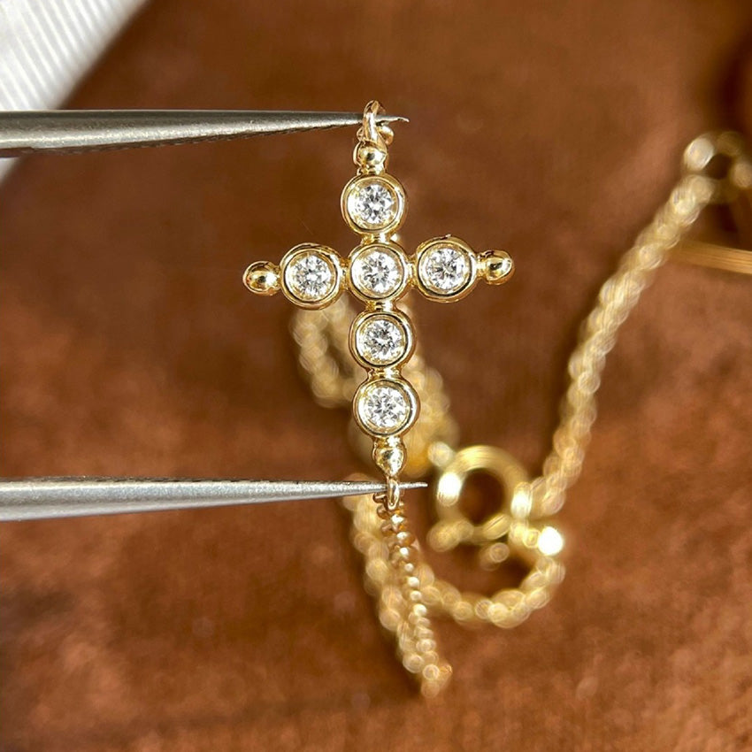 Two dainty gold chain bracelets with cz cross charms on model wrist for wholesale stacking jewelry display