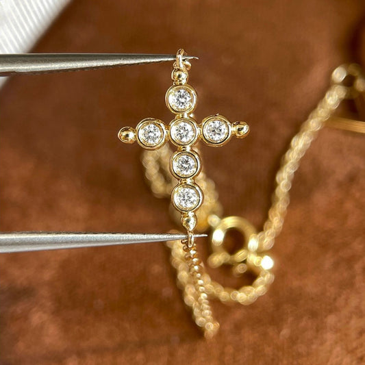 Two dainty gold chain bracelets with cz cross charms on model wrist for wholesale stacking jewelry display