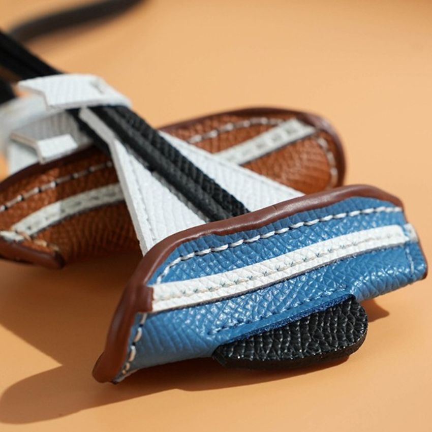 Close-up of blue leather sailboat charm with stitched details