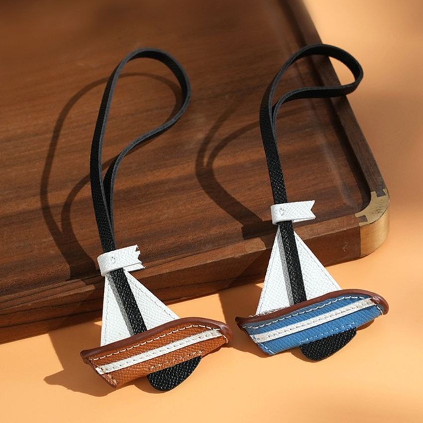Brown leather sailboat charm with white sail detail