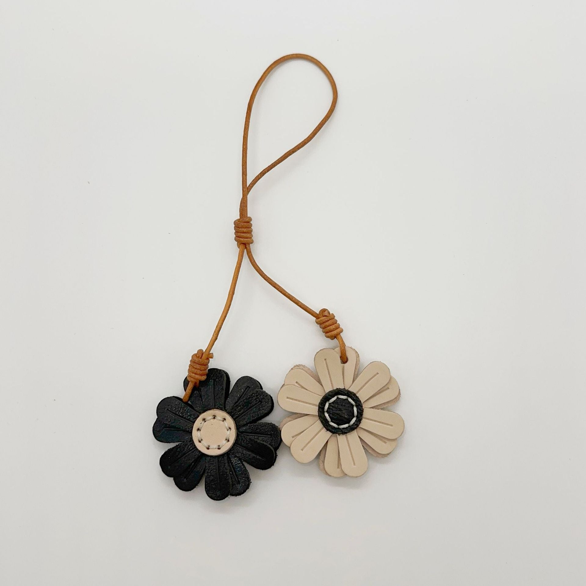 Handmade leather sunflower bag charm in beige and black tones, cute daisy leather keychain for handbags and car mirror decoration.