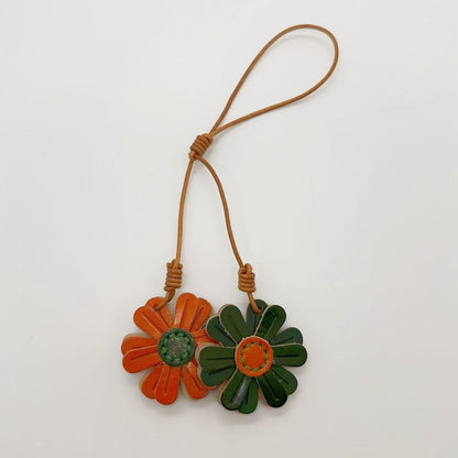 Green and orange daisy leather keychain set, perfect leather bag charm wholesale item for boutiques and car rearview mirror charm displays.