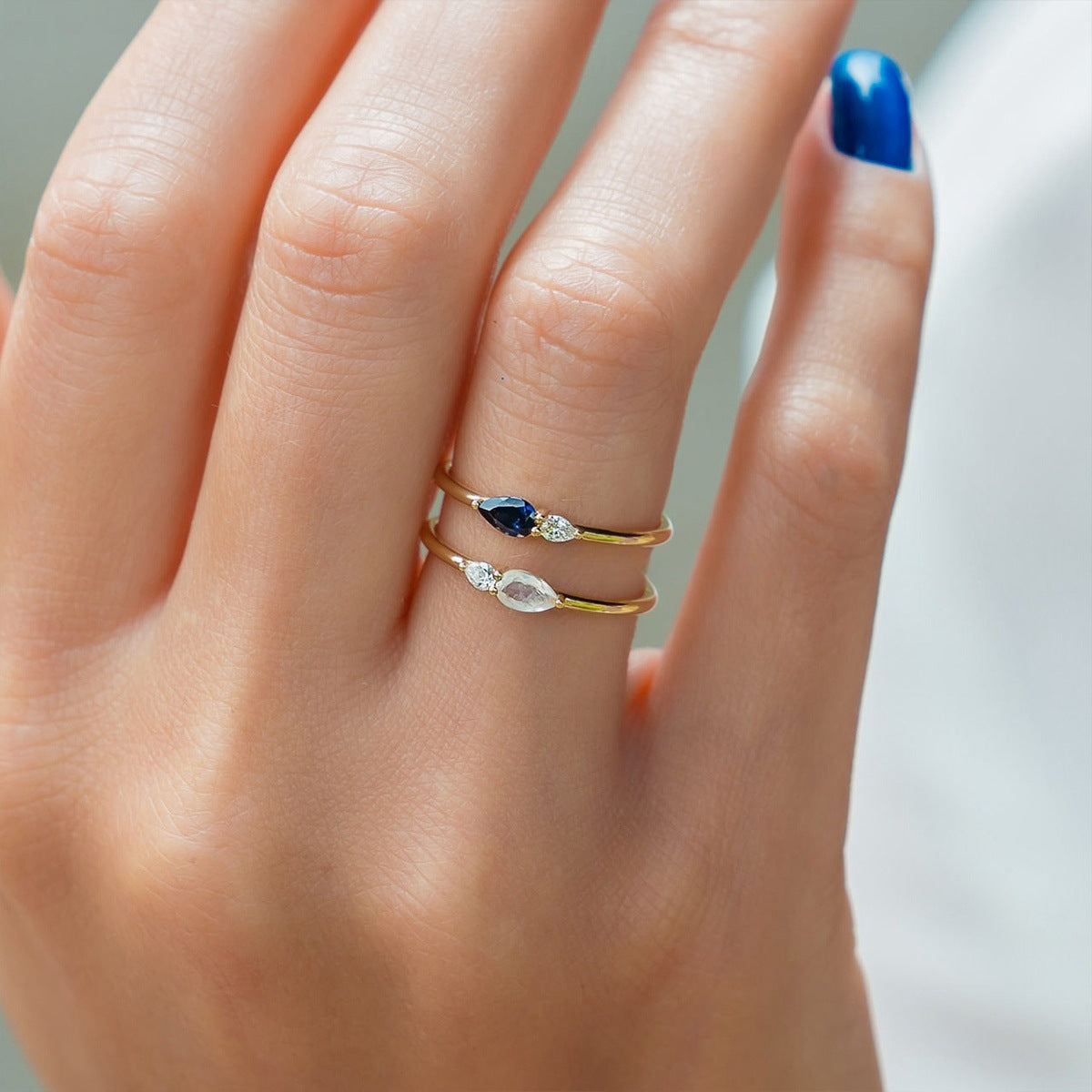 Close up of 18K gold plated sterling silver ring with blue pear cut zircon and sparkling clear zircon