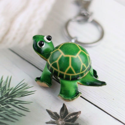 Green turtle leather keychain with yellow shell pattern on wood surface