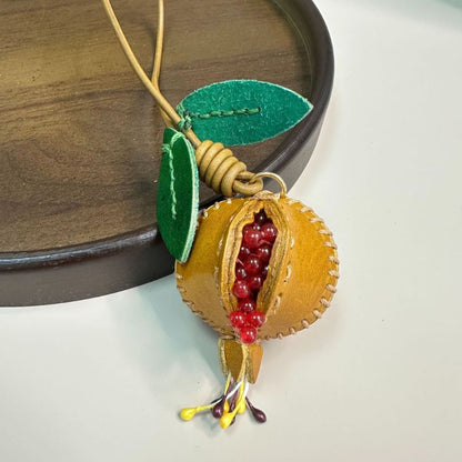Set of red and yellow genuine leather pomegranate charms hanging on handbag, handmade leather bag charm design perfect for fruit bag charm wholesale, fashion accessories wholesale, and seasonal gift collections.