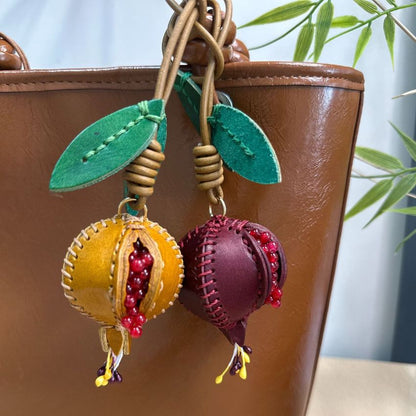 Purple handmade genuine leather bag charm shaped like pomegranate with red bead details and green leaves, ideal as fruit bag charm, car rearview mirror charm, or handbag decoration for bag charm wholesale gift sets.