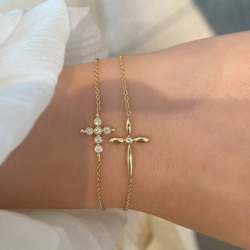 Delicate gold chain cross bracelets stacked on wrist demonstrating premium quality for bulk purchase