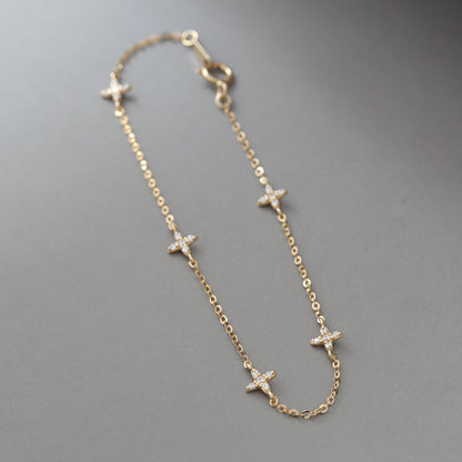 Diagonal layout of dainty gold silver star charm bracelet on gray background showing spring ring clasp