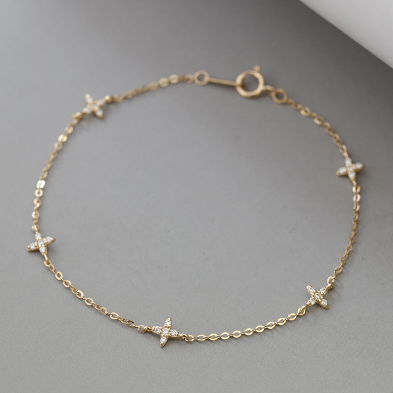 Minimalist 18k gold plated sterling silver starry flora cz bracelet laid flat on gray surface for retail catalog