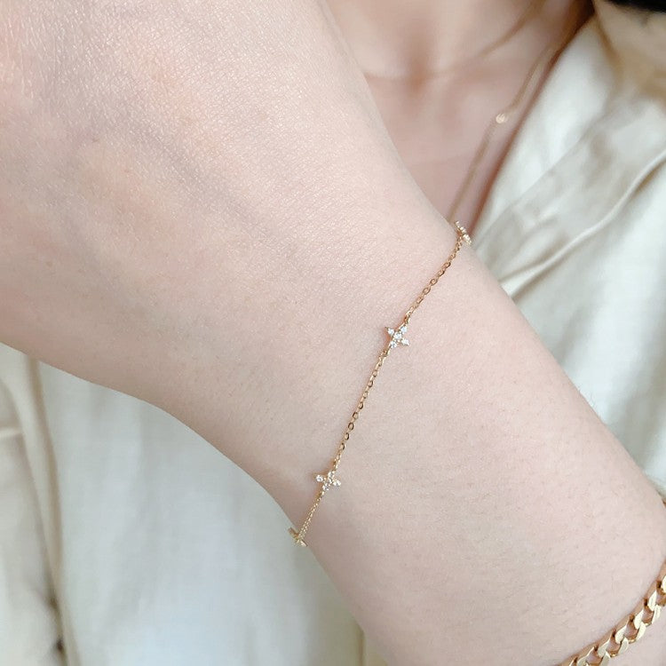 Ethereal S925 gold plated silver chain bracelet with cz star floral charms on model wrist for wholesale display