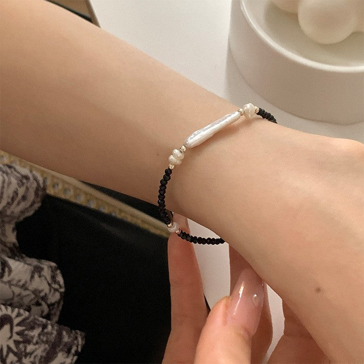 Front wrist view of an S925 bracelet with black spinel beads and a long irregular pearl