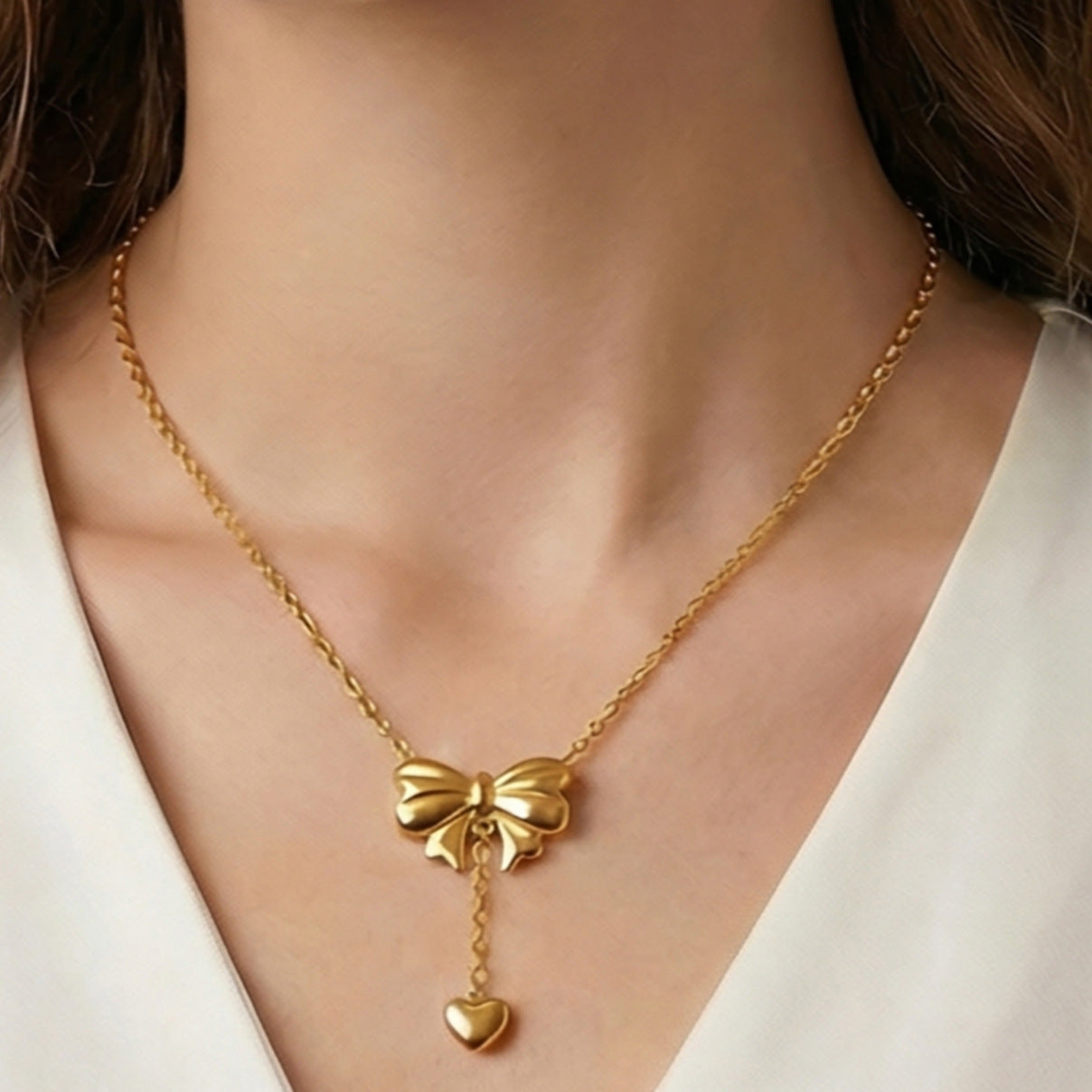 Bow necklace and earring set on model gold tone bow pendant with heart tassel drop