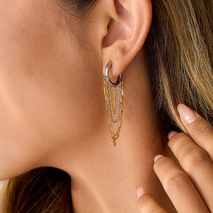 Model wearing mixed metal hoop earrings with layered chain tassel drop