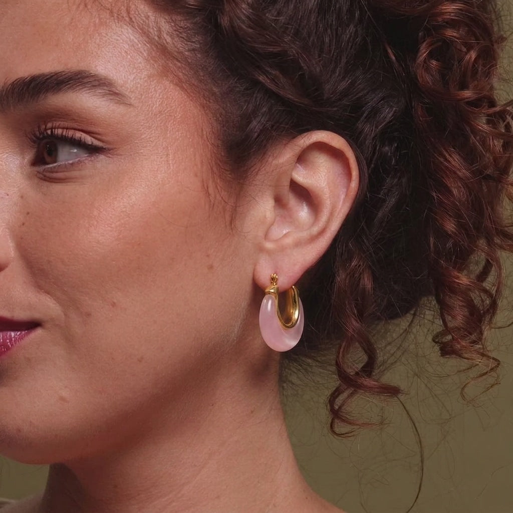Rose pink resin hoop earrings with gold tone stainless steel worn on the ear