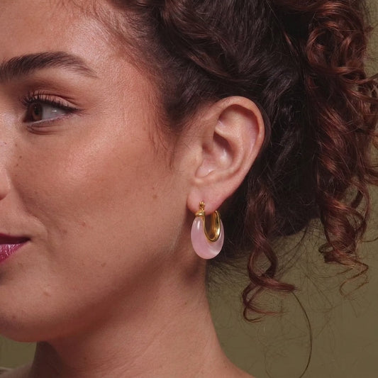 Rose pink resin hoop earrings with gold tone stainless steel worn on the ear