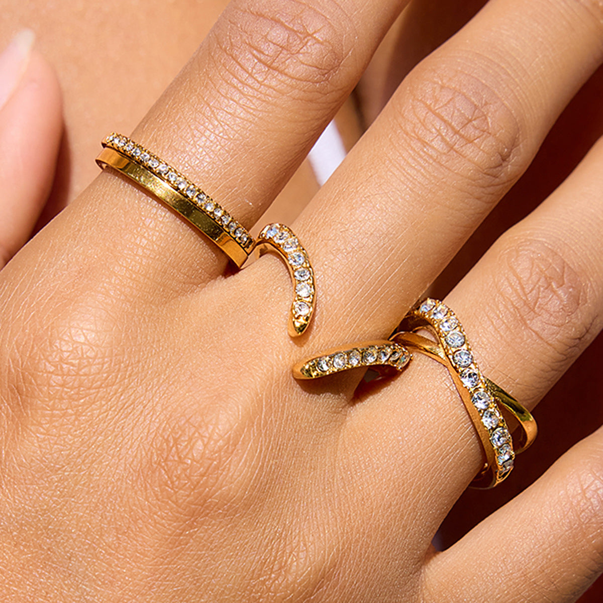 Close view of gold stainless steel crisscross zircon rings worn on hand
