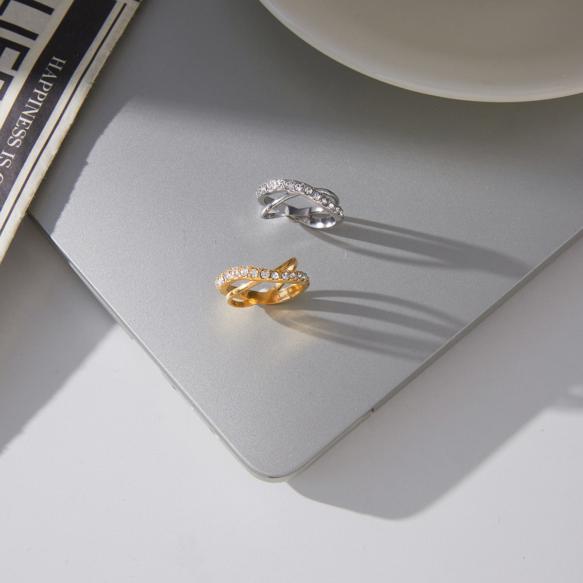 Gold and silver stainless steel crisscross zircon rings on display surface