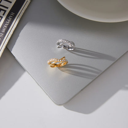 Gold and silver stainless steel crisscross zircon rings on display surface