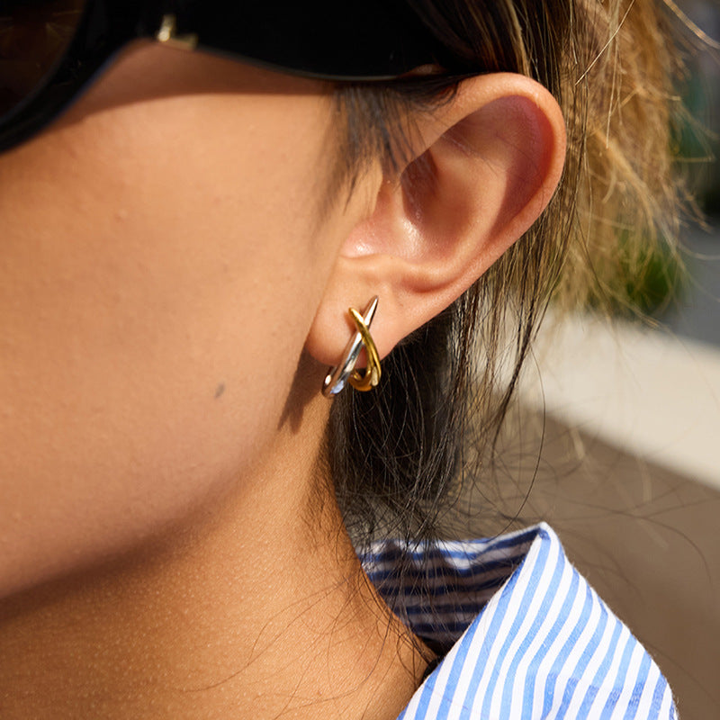 Model wearing gold and silver tone crossed line stainless steel earrings close up view