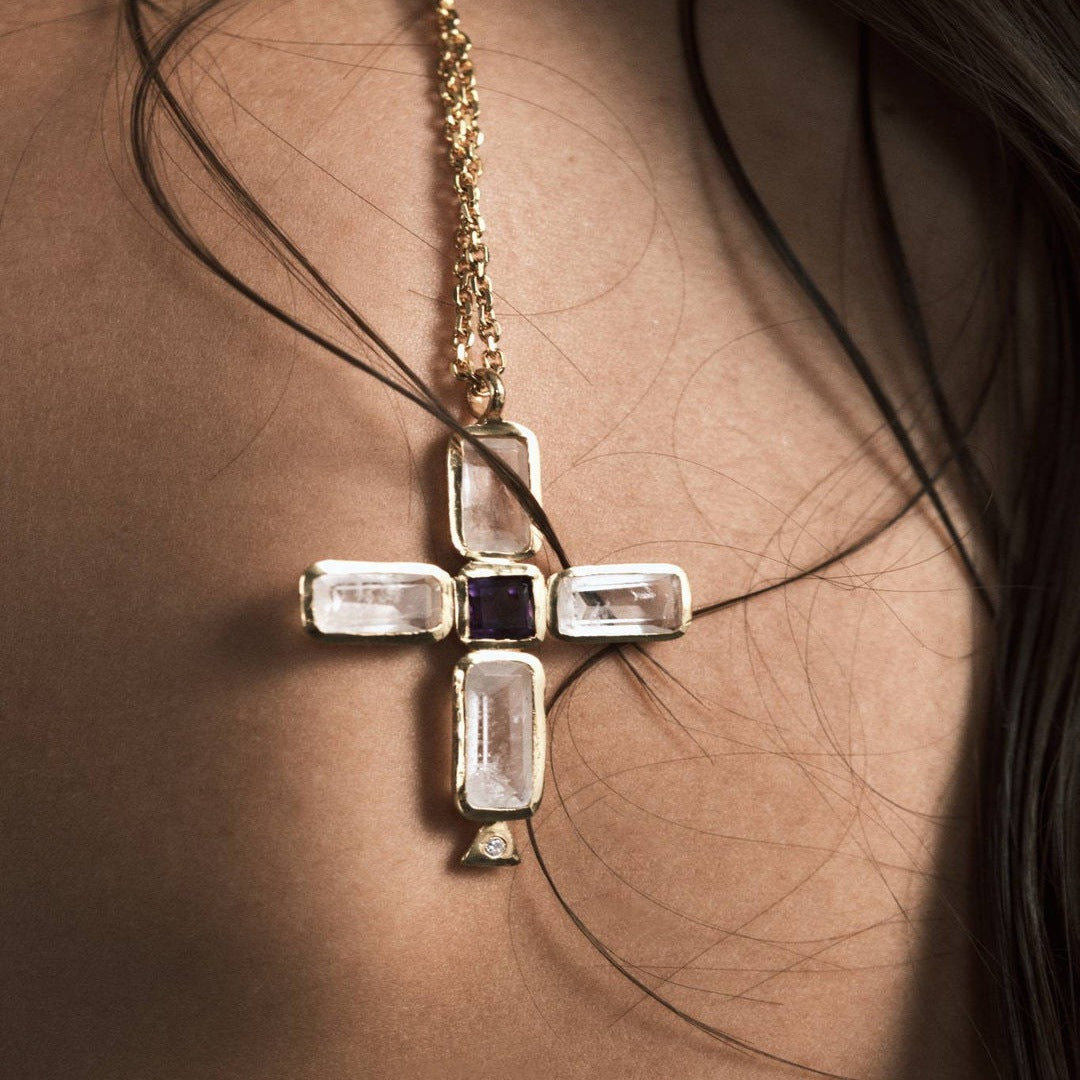 Model wearing gold tone luxury cross necklace with baguette style stone cross pendant
