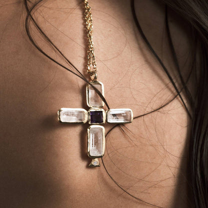 Model wearing gold tone luxury cross necklace with baguette style stone cross pendant