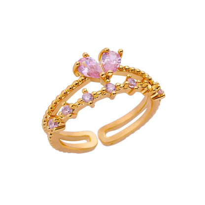 Gold tone adjustable open ring with pink bow style stone and crystal details
