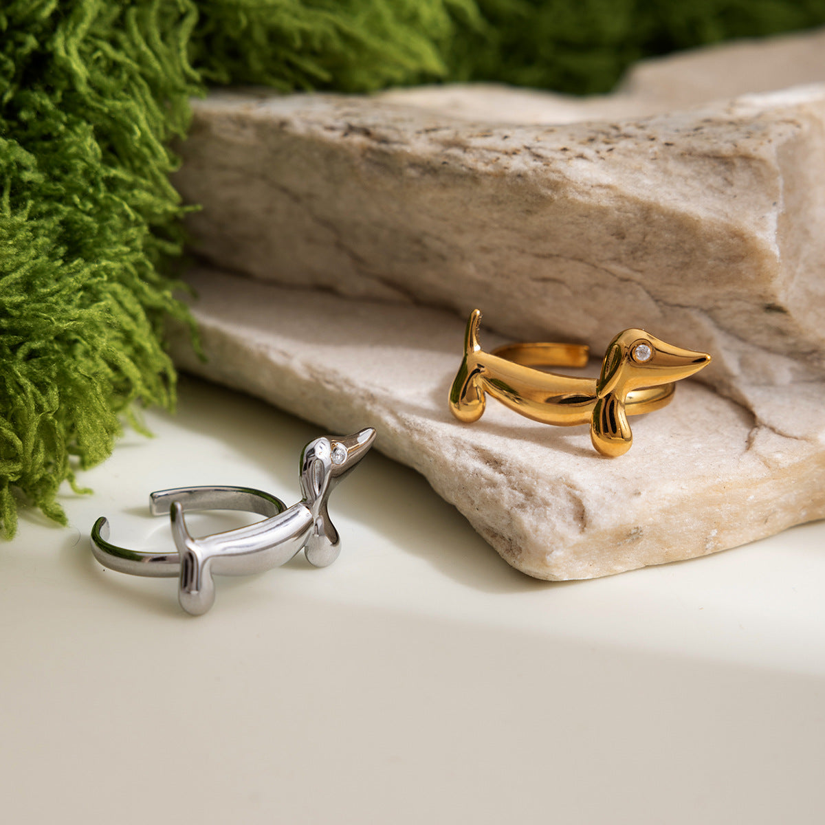 Gold and silver dachshund open rings with small clear stone detail on stone backdrop