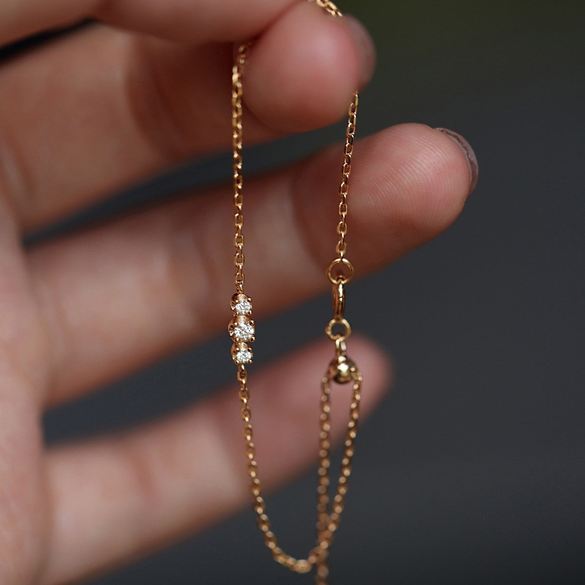 Gold plated silver cubic zirconia chain bracelet with adjustable bead slider clasp held by hand