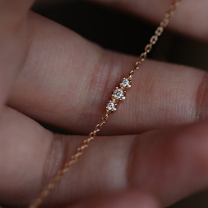 Close up of three sparkling cubic zirconia stones on an ultra thin gold chain bracelet for retail catalog