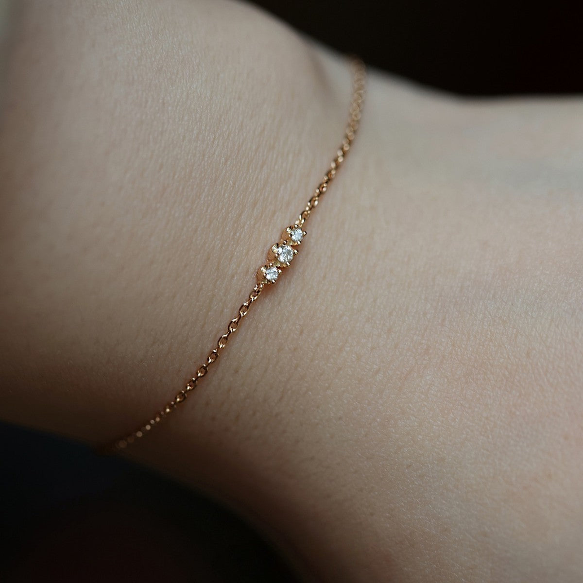 Close up of two dainty gold cz chain bracelets showcasing fine bezel settings for bulk jewelry buyers