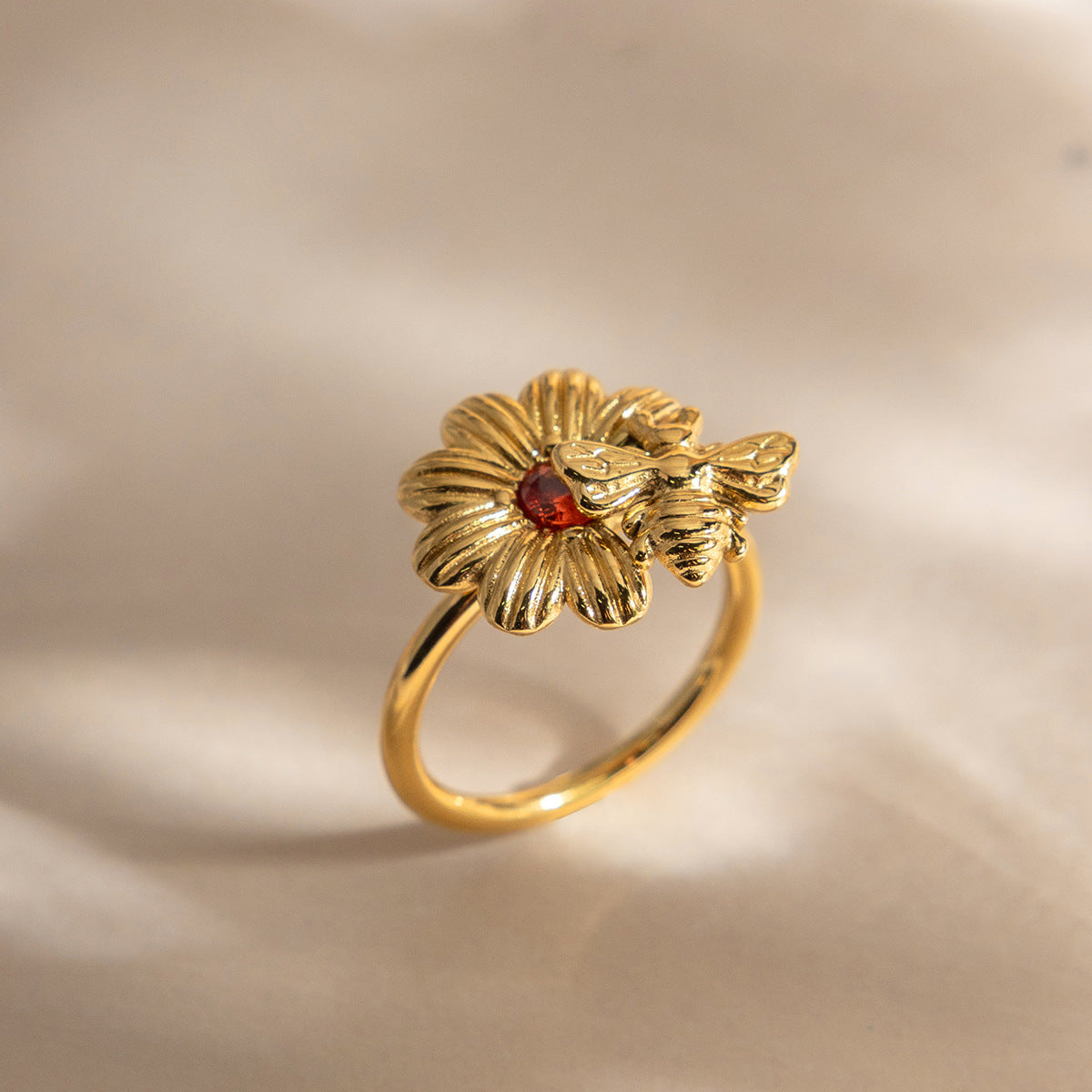 Wholesale stainless steel bee daisy ring with orange zircon on neutral background