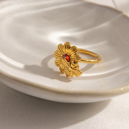 Close view of wholesale stainless steel bee daisy ring with orange zircon on plate